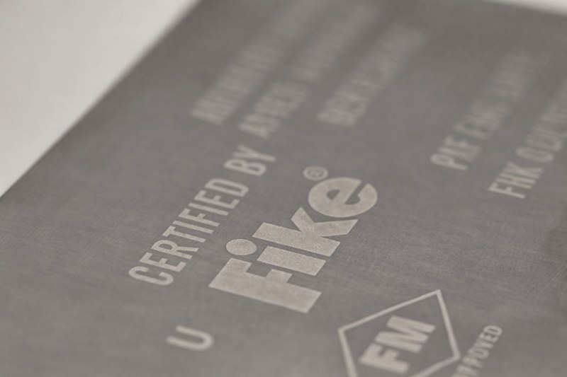 Stainless steel certification nameplate manufactured by Metallics, Inc. for Fike, featuring etched certification text and an FM Approved mark.