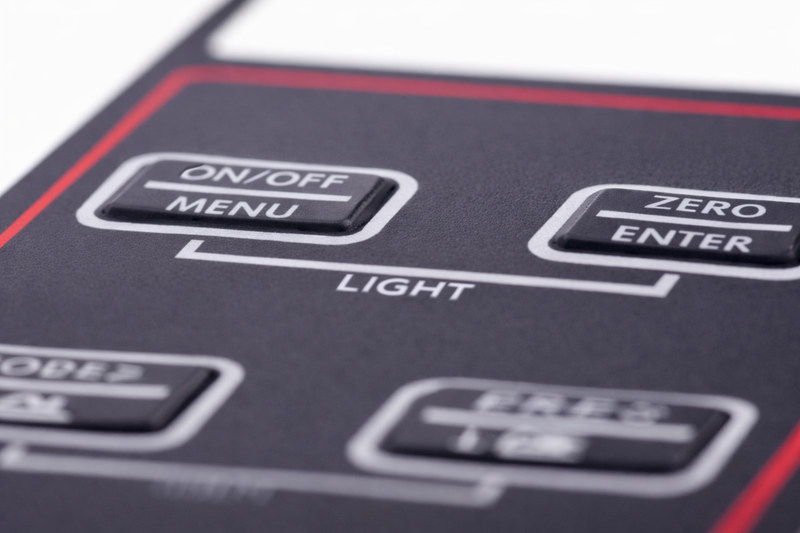 Black polycarbonate control panel overlay manufactured by Metallics, Inc. with embossed buttons labeled On/Off, Menu, Zero, Enter, and Light.